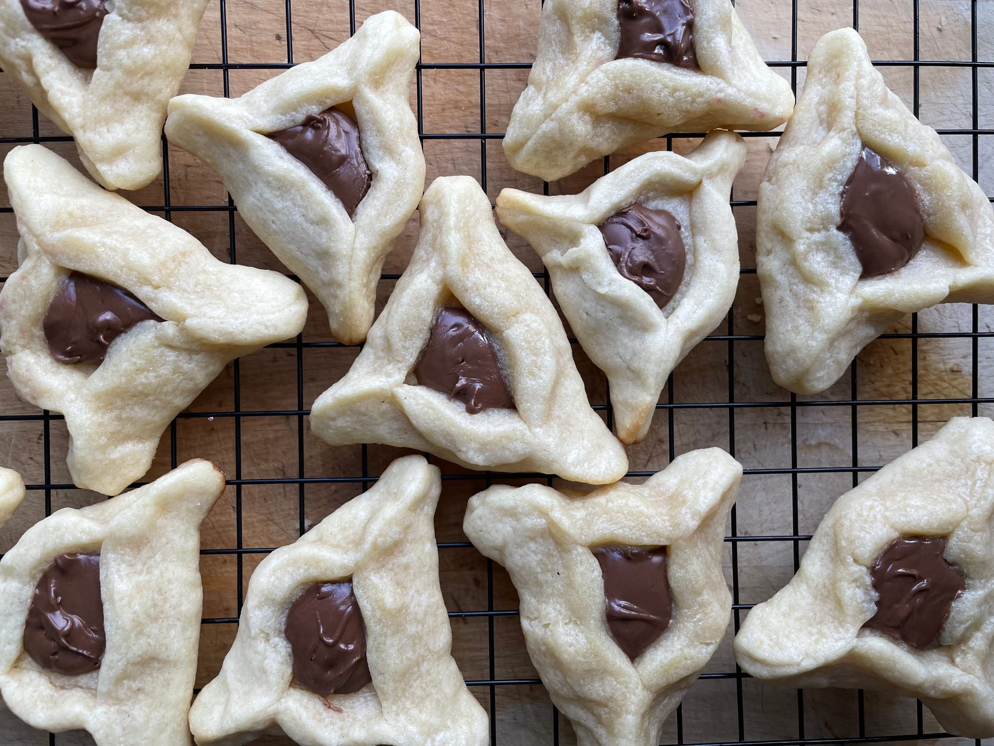 Triangular cookies filled with Nutella on a black wire cooling rack