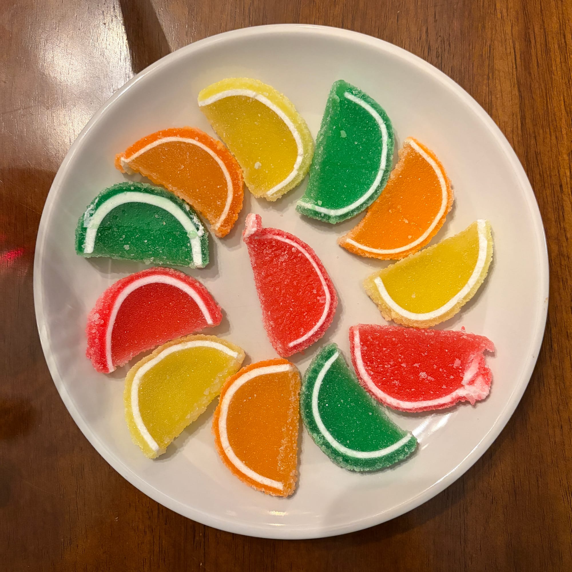 White plate with a pinwheel arrangement of colorful candy fruit slices