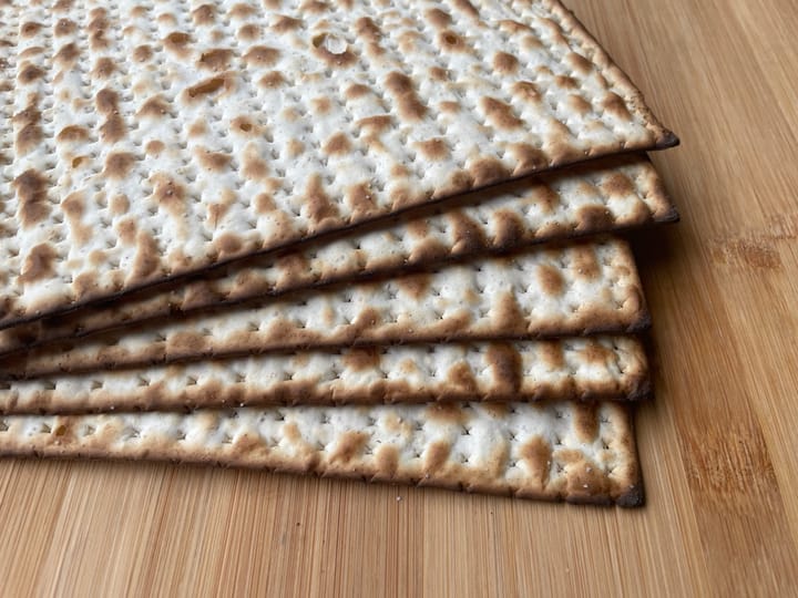 Five pieces of matzah on a wooden cutting board